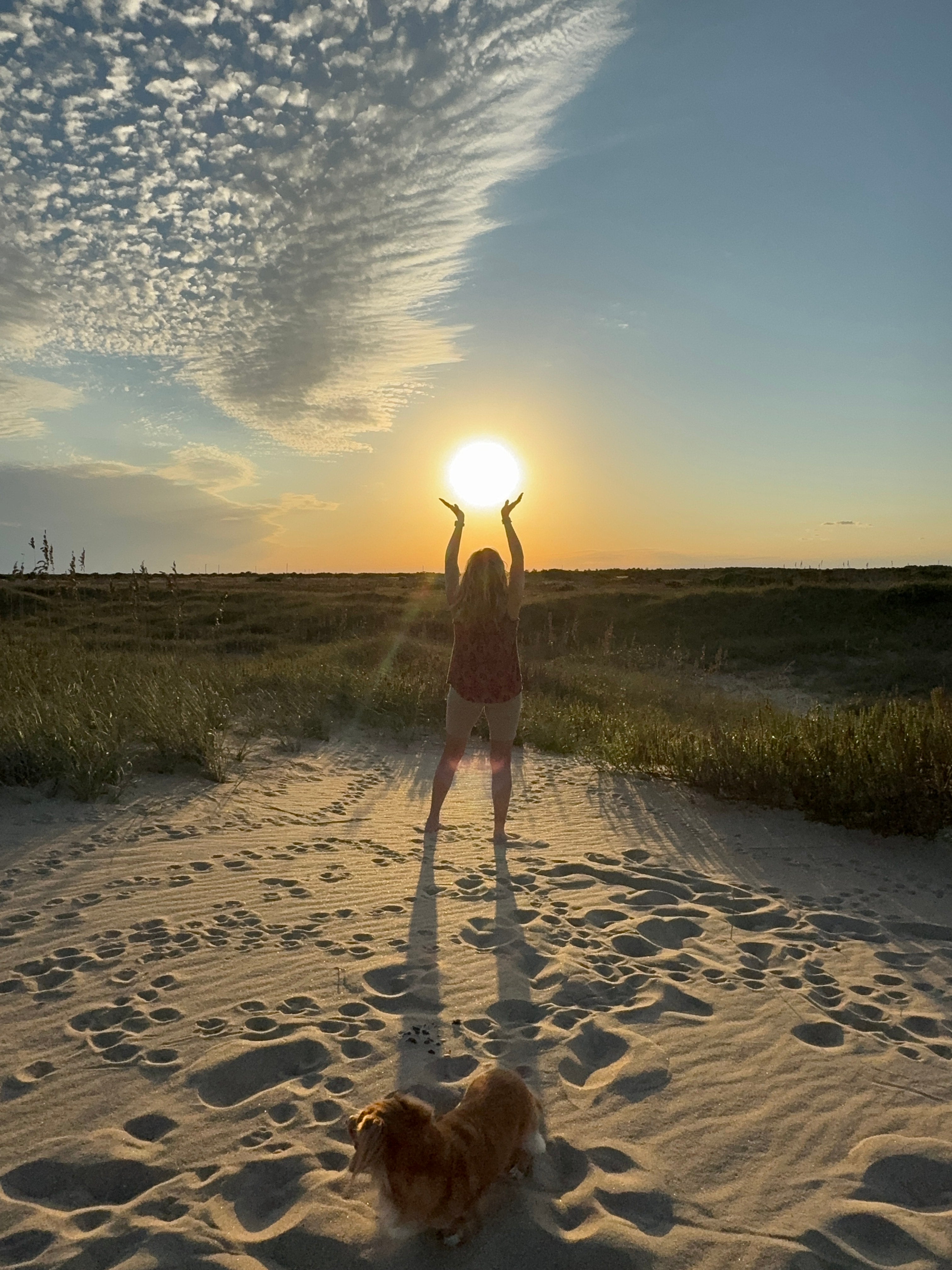 Woman holding sunset on the beach